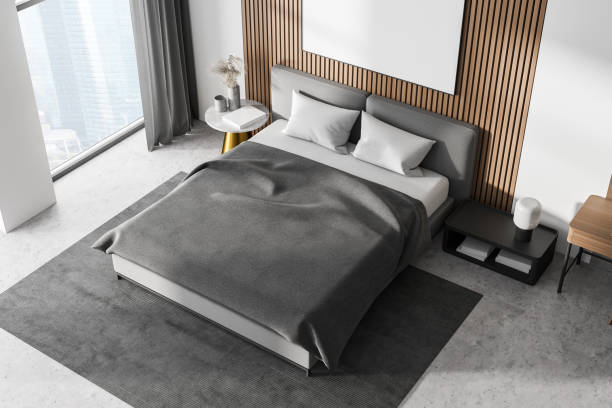 istock White bedroom interior with concrete floor, a large window, a gray bed and two bedside tables. Top view. Poster on wooden wall. mock up 1309602261