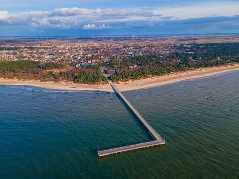 Aerial view of Palanga pedestrians bridge to the sea and coastline with sandy beach and blue cloudy sky. View from the sea side