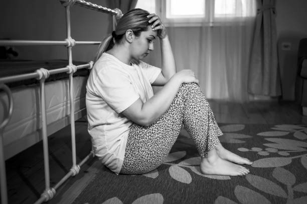 istock Depressed woman sitting on the floor 1309604875