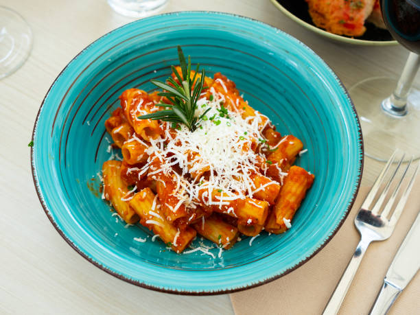 Rigattone amatraciana Italian pasta amatricana with tomato sauce and goat cheese on a blue ceramic plate in a restaurant all'amatriciana stock pictures, royalty-free photos & images