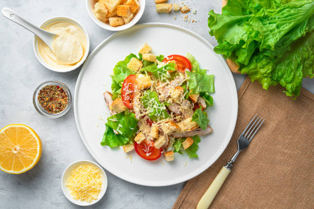 istock Traditional Caesar salad with croutons and fresh vegetables on a gray background. Top view, horizontal 1309604978