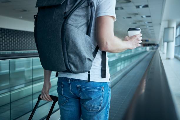 uomo che cammina con una tazza di caffè di carta al terminal dell'aeroporto - moving walkway escalator airport walking foto e immagini stock