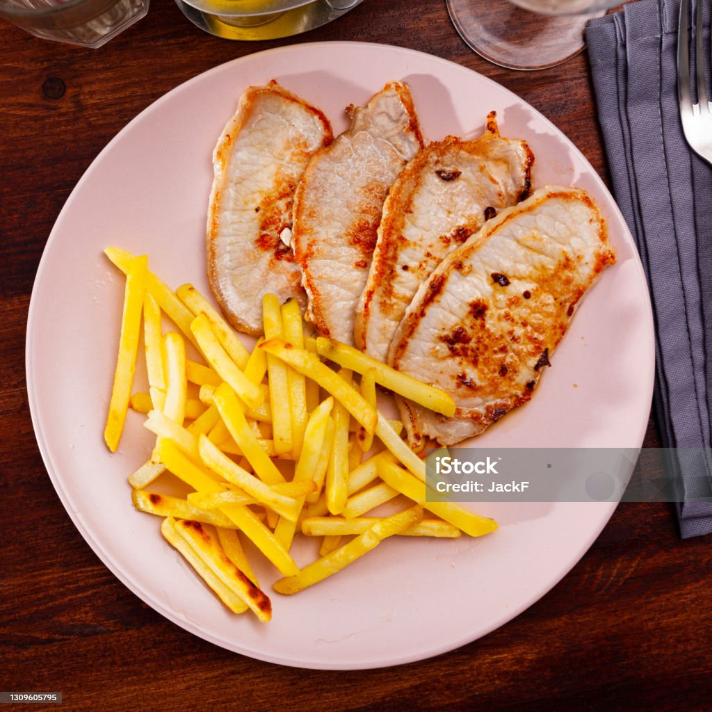 Fried barbecue pork meat with baked potato Fried barbecue pork meat with baked potato on a plate in a pub Barbecue - Meal Stock Photo