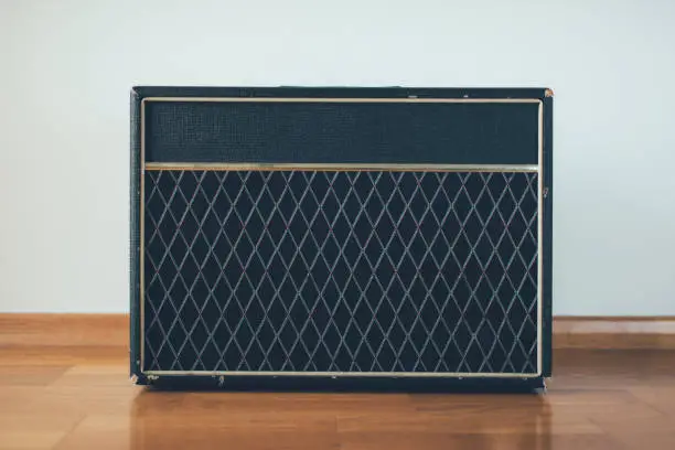 Classic guitar amplifier at white wall background.