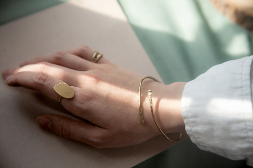 sophisticated female hand with Hammered brass Copper ethnic bracelet and gold vintage stylish polished ring. Ancient times type jewelry accessories concept. Selective soft focus