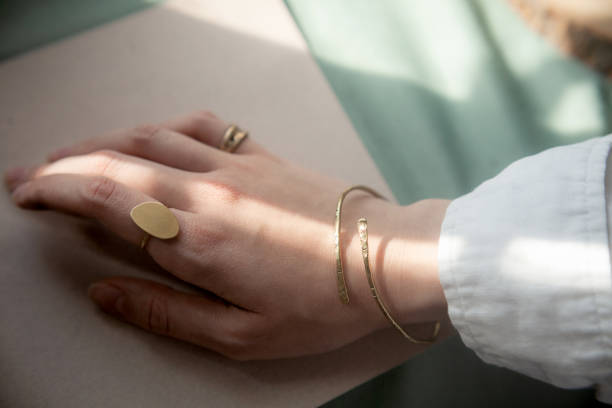 kvinnlig hand med mässing koppararmband och guld vintage snygg polerad ring - hand gold jewels bildbanksfoton och bilder