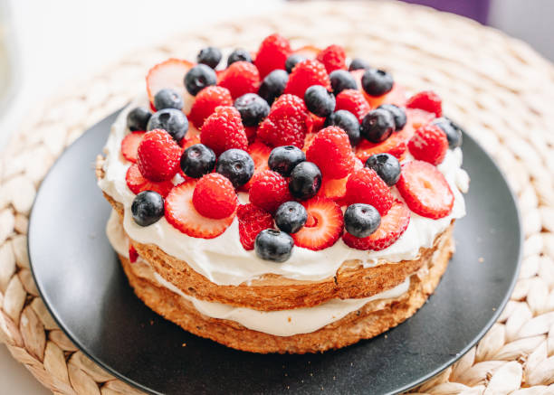 istock Meringue cake with fresh forest berries and cream on black plate 1309606079
