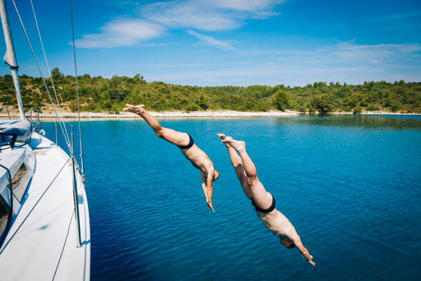 istock Men jumping in sea from sailboat 1309608971