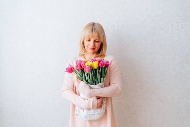 istock Beautiful mature woman holding tulips 1309610521