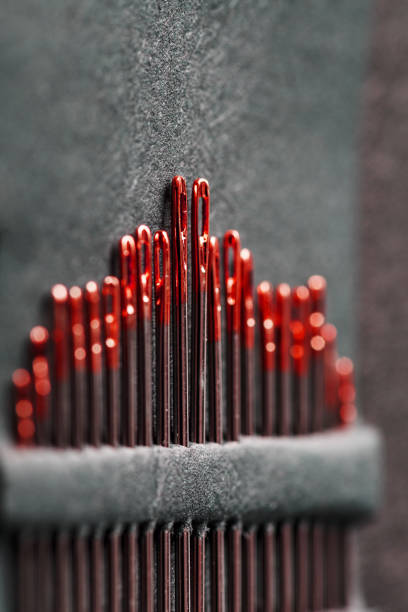 istock Sewing needles of different sizes in a set of red on a black background. 1309611686