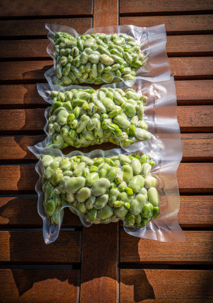 Broad Beans also Lima Beans peeled in vacuum sealed plastic bag ready to be frozen on wooden table just after hasvested and peeled