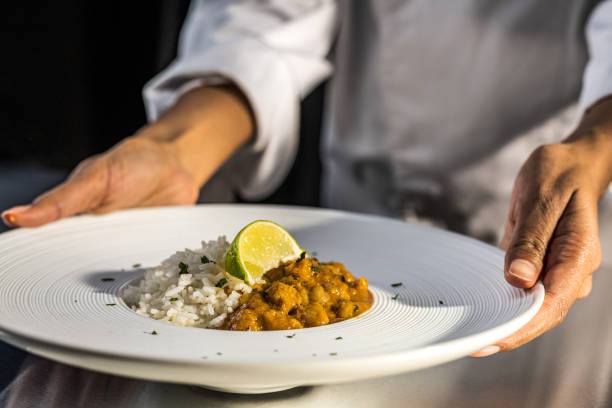 istock Chef holding white modern design plate with rice and vegetable sauce. Cooking without meat. 1309616433