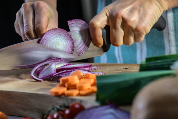 istock Cutting thin slices of purple onion on wooden cutting board. Using local sources in kitchen. 1309616487