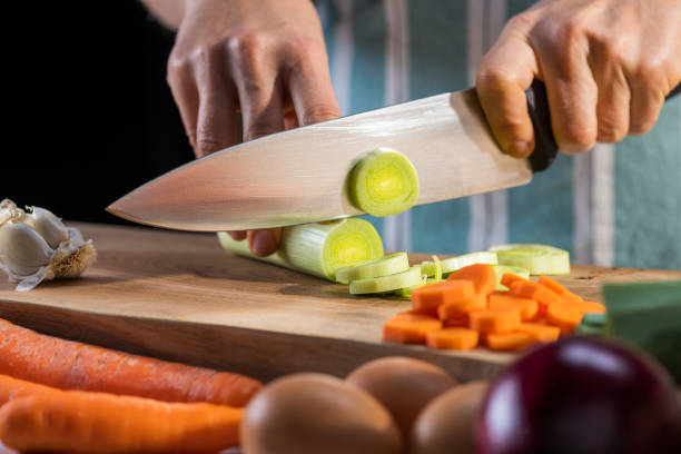 istock Cutting vegetable ingredients for cooking in kitchen. Male hands preparing leek. 1309616490