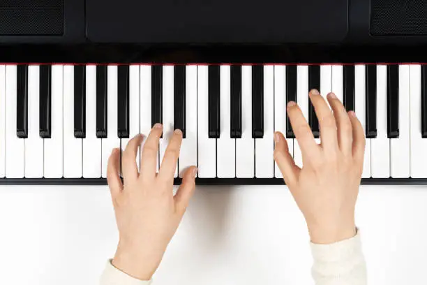 Photo of Kid hands learning to play on the piano. Top view