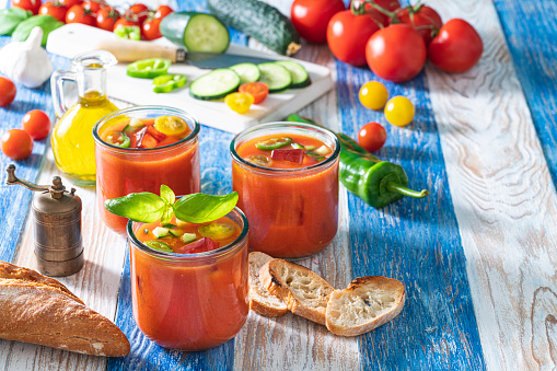 Gazpacho andaluz cold tomato soup recipe in a glass from Andalusian Spain on summer wooden board of blue and white stripes