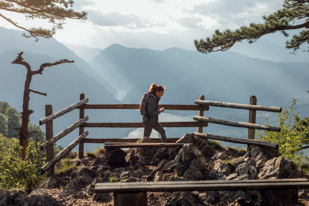 Woman Hiker at a Stunning Mountain Viewpoint A young female hiker with a backpack standing at a breathtaking viewpoint, a side view. splash mountain stock pictures, royalty-free photos & images