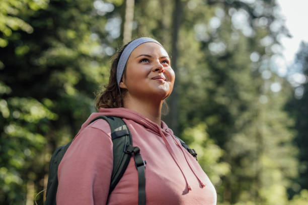 Portrait of a Beautiful Woman Hiker Smiling Happy woman with a backpack spending a day in nature, a portrait. body positive stock pictures, royalty-free photos & images