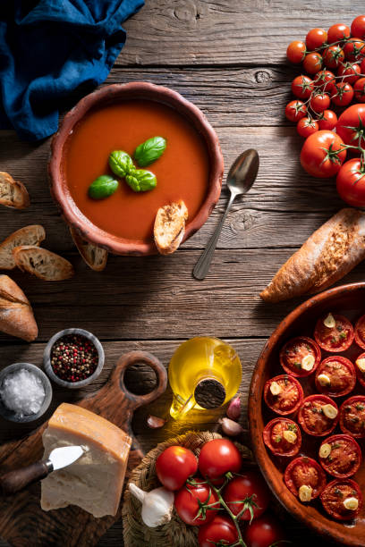 istock Tomato soup with roasted tomatoes, basil, ingredients  and toasted bread on rustic wood 1309618860