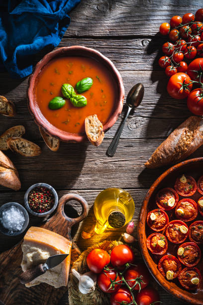 istock Tomato soup with roasted tomatoes, basil, ingredients  and toasted bread on rustic wood 1309618878