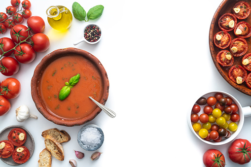 Tomato soup with roasted tomatoes, basil, ingredients and toasted bread isolated on white background