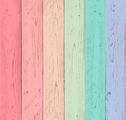 A rustic looking wooden boards painted in pastel shades of red, pink, orange, green, blue and violet. background for wedding themes and rustic events in the countryside.