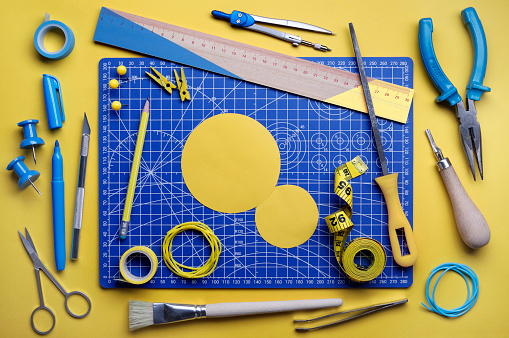 Various yellow and blue DIY supplies on cutting mat.