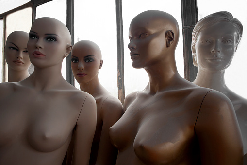 Group of Mannequins standing together in front of a window. The mannequins do not have clothes.