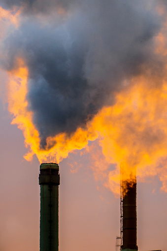 The sun goes down behind chimneys in a factory