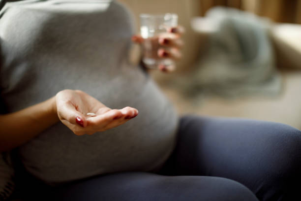 istock Pregnant woman taking pill at home 1309623342