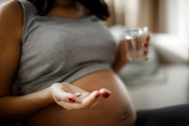 istock Pregnant woman taking pill at home 1309623484