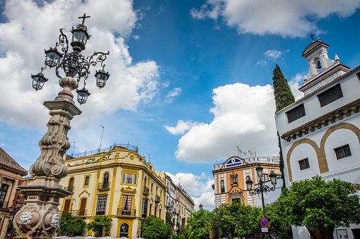 View of the fountain of the lamppost and buildings in the Plaza de la Virgen de los Reyes, next to the Cathedral of Seville.