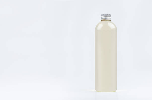 istock Transparent plastic tall thin bottle with pale fresh drink or cosmetic essential oil, silver cap mockup on white background. 1309627790