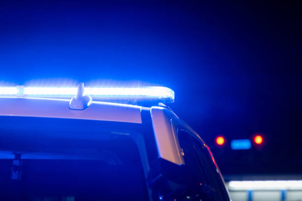 Blue police lights on a car Blue lights on top of a police car with a red traffic light in the background. police vehicle lighting stock pictures, royalty-free photos & images
