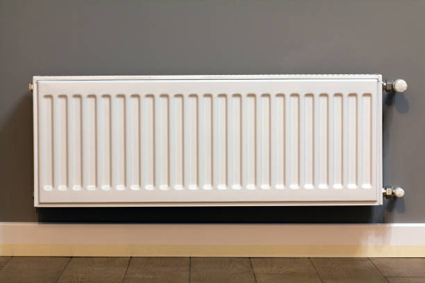 istock White metal heating radiator mounted on gray wall inside a room. 1309633573