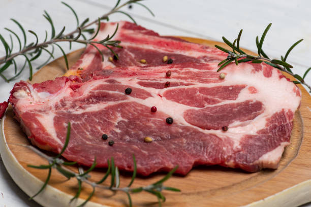 A single piece of raw pork loin is showcased, exhibiting a pinkish hue with streaks of white fat along the edge. The meats texture is clearly visible, and it is presented against a stark white backdrop, emphasizing the cuts freshness and quality.