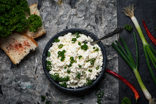Crumbled young cow cheese in a bowl with spring onion and food ingredients