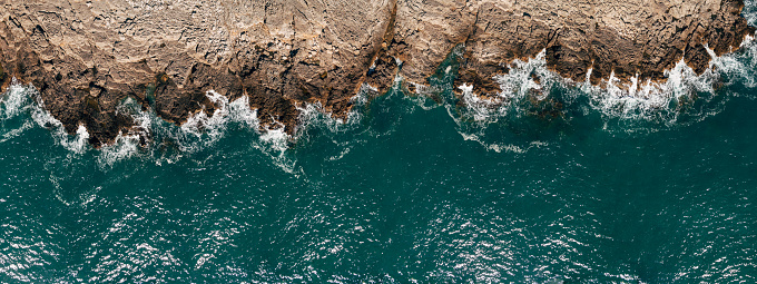 Wild ocean waters from above, waves hitting rocks - aerial photography. High quality photo