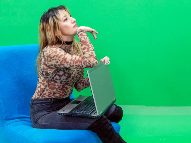 Woman posing with laptop with green background