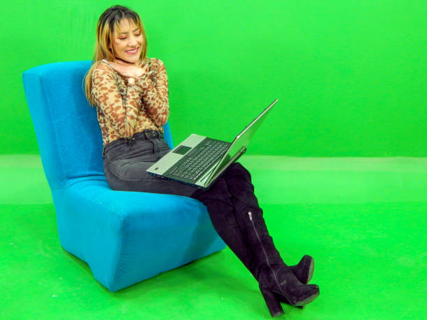 istock Woman posing with laptop with green background 1309638331