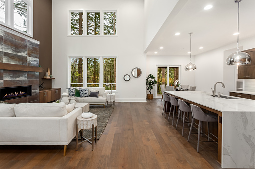 Hermosa sala de estar y cocina en nueva casa de lujo con isla cascada, luces colgantes y pisos de madera noble. photo