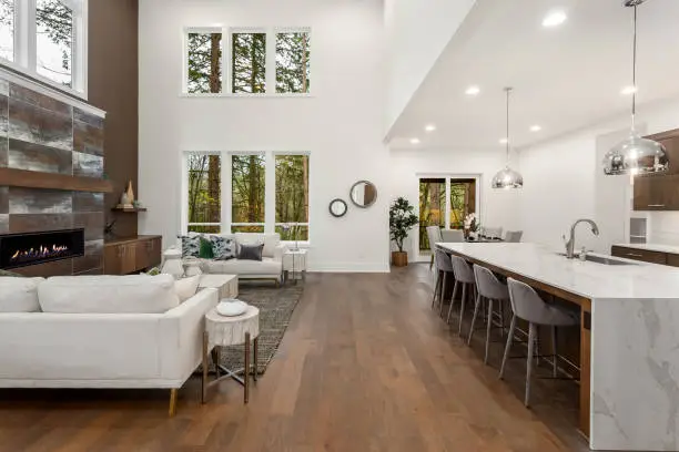 Photo of Beautiful living room and kitchen in new luxury home with waterfall island, pendant lights and hardwood floors.