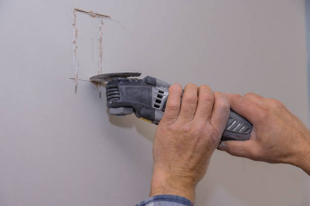 istock Man cutting gypsum drywall cut holes on using angle hand electric power tools for wall light switch electrician 1309646748