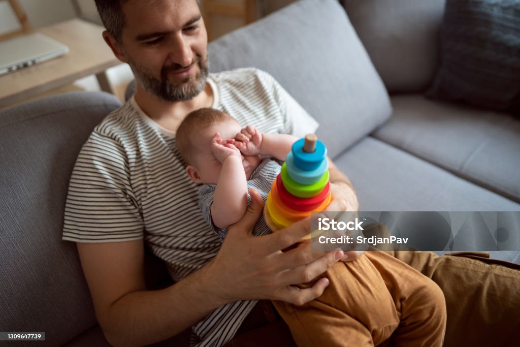 All that play makes me sleepy Happy Caucasian father using his free time for bonding with his baby son. Plastic Ring Stock Photo