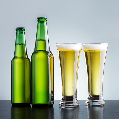 Two Beer Glass And Bottle On A Dark Wooden Table.