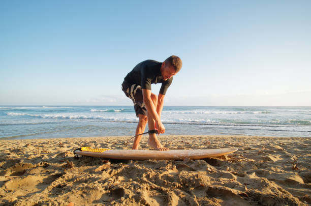 istock Surfer man fastens leash at leg, going to surf in ocean. 1309663721