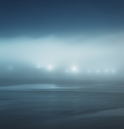 A distant pier is shrouded in heavy fog.