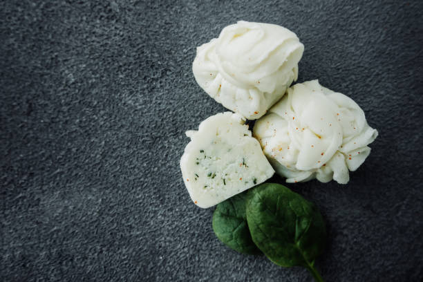 Georgian homemade cottage cheese in bag with herbs , fresh basil leaves on a dark table. national dishes of Georgia. Types of cheese products. Vertical content, close, selective focus