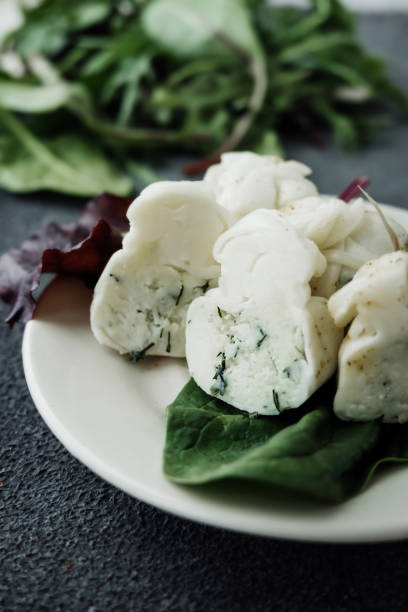 selective focus Georgian cottage cheese with herbs and garlic, with basil leaves on dark cement table. national dishes of Georgia. Types of cheese products. Vertical content