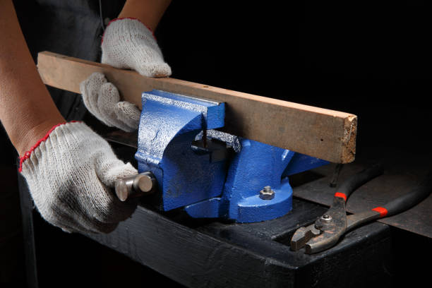istock Closeup workers hands on a  wooden plank locked in the iron vise 1309672847